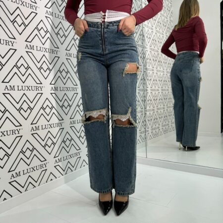 Jeans con strappi e la vita decorata con merletto e bottoncini dona un tocco di eleganza e originalità, mentre gli strappi leggeri aggiungono un effetto di adereza.