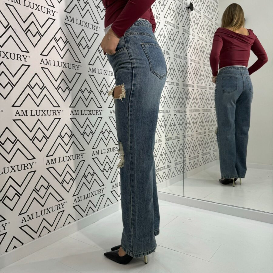 Jeans con strappi e la vita decorata con merletto e bottoncini dona un tocco di eleganza e originalità, mentre gli strappi leggeri aggiungono un effetto di adereza. - immagine 2
