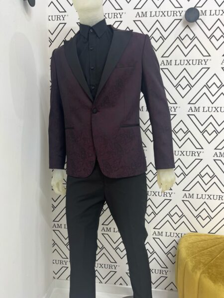 Vestito con giacca damascata, dona profondità e lusso al capo, mentre la tonalità bordeaux aggiunge eleganza senza tempo, mentre il pantalone si presenta semplice a gamba dritta.