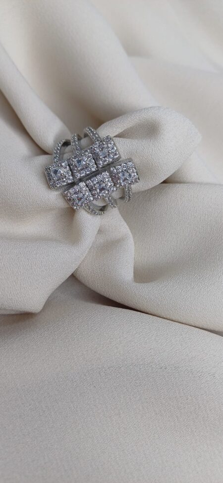 Anello color argento con sei quadrati geometrici e pietre al centro disposti frontalmente.