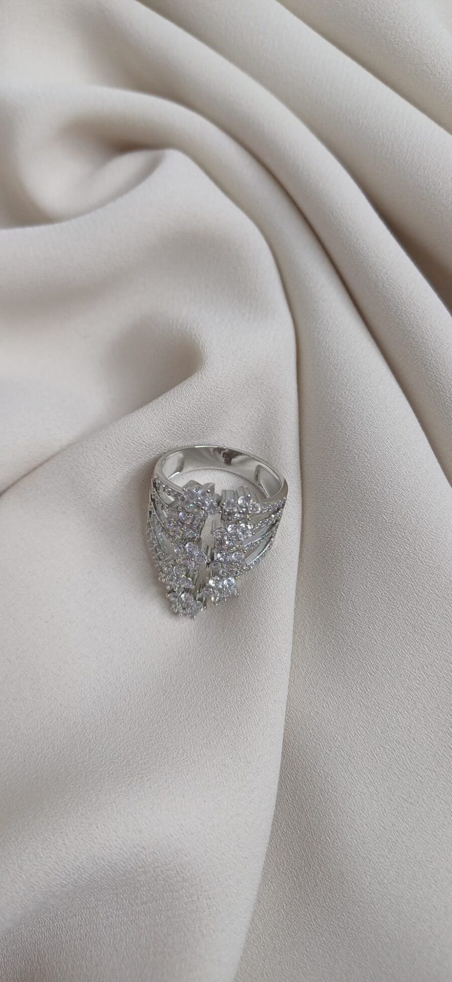 Anello color argento caratterizzato da nove piccoli fiori disposti in modo speculare con al centro una pietra brillante - immagine 3