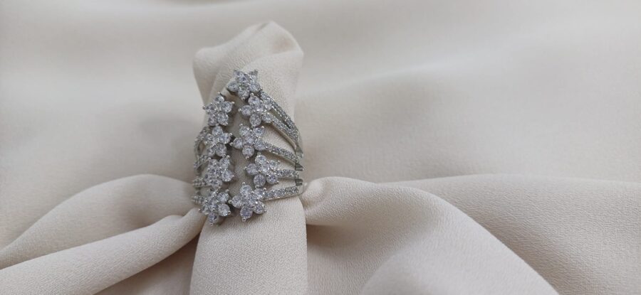 Anello color argento caratterizzato da nove piccoli fiori disposti in modo speculare con al centro una pietra brillante - immagine 4