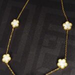 Collana color oro con ciondoli floreali bianco lucido, chiusura regolabile